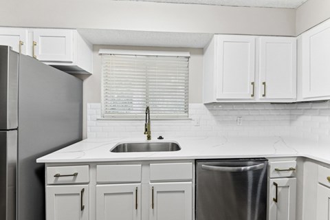 a kitchen with white cabinets and a sink and a window